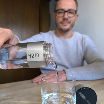 Anwendung Wasserstoffbooster H2Master Mann mit Glas Anwendung Wasserstoffbooster H2Master Mann mit Glas