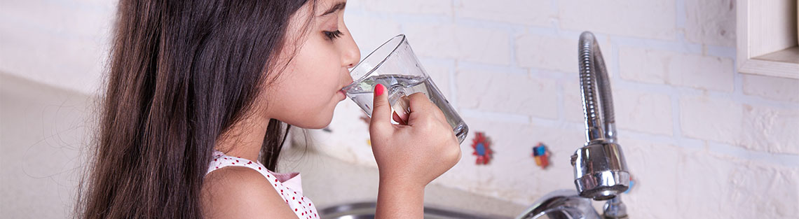 Mädchen trink Wasser am Wasserhahn